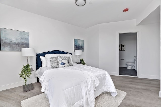 bedroom with ensuite bath and hardwood / wood-style flooring