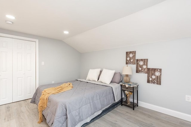 bedroom with hardwood / wood-style flooring, a closet, and lofted ceiling