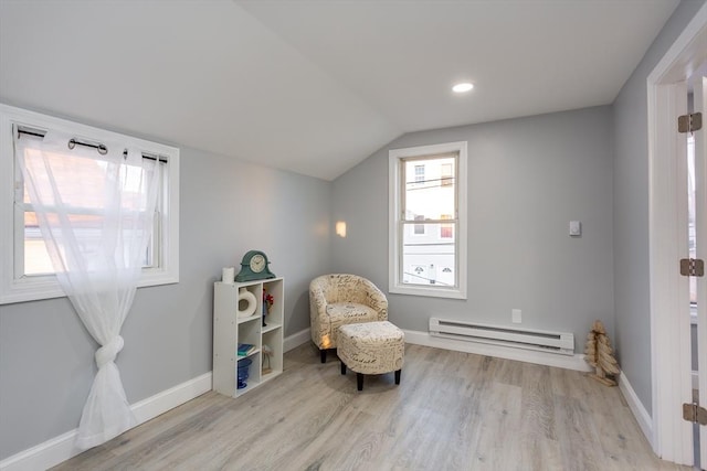 sitting room with light wood-type flooring, vaulted ceiling, and a baseboard heating unit