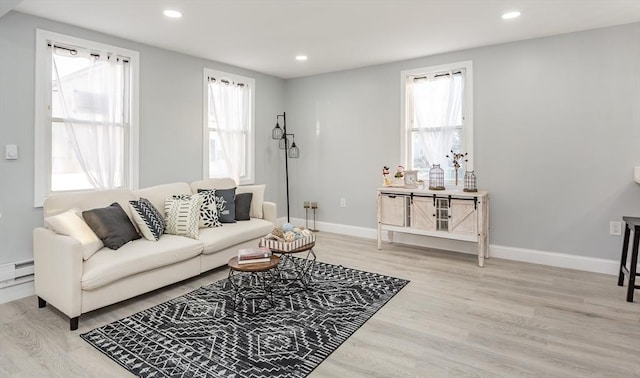 living room featuring a healthy amount of sunlight, a baseboard heating unit, and light wood-type flooring