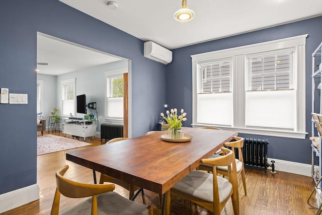 dining space with radiator, a wall unit AC, baseboards, and wood finished floors