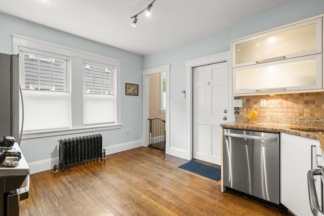 kitchen featuring stainless steel dishwasher, radiator heating unit, tasteful backsplash, wood finished floors, and baseboards