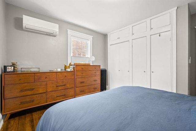 bedroom with a wall mounted air conditioner and dark wood finished floors