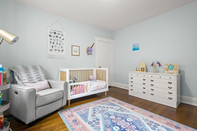 bedroom featuring wood finished floors, baseboards, and a nursery area