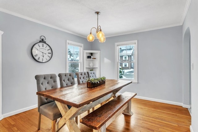 dining area featuring an inviting chandelier, ornamental molding, and light wood-type flooring