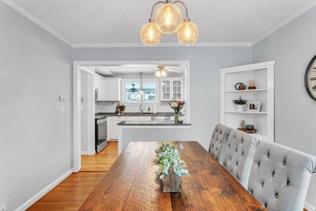 dining area with ceiling fan, ornamental molding, sink, and light hardwood / wood-style floors