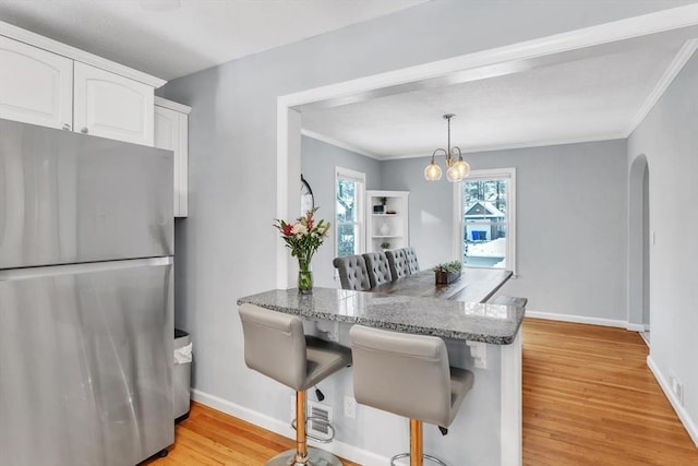 dining room with an inviting chandelier, ornamental molding, and light wood-type flooring