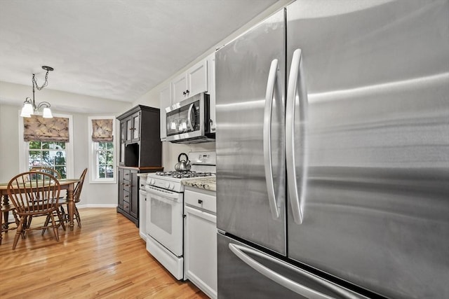 kitchen with appliances with stainless steel finishes, light wood-style flooring, pendant lighting, white cabinetry, and baseboards