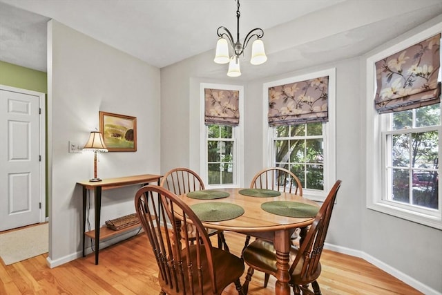 dining area with a chandelier, healthy amount of natural light, light wood-style floors, and baseboards
