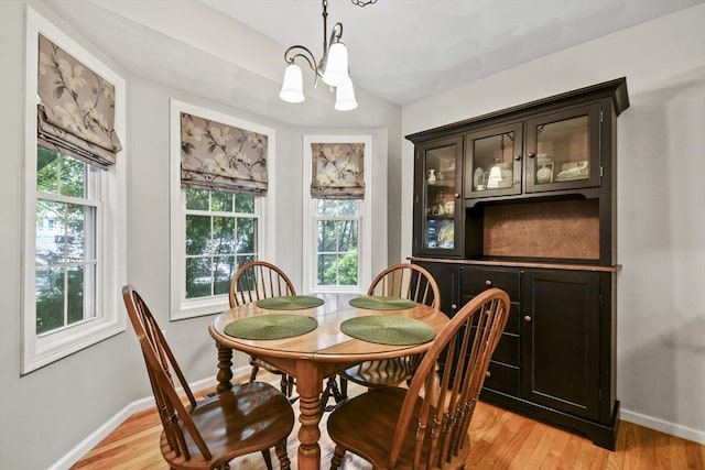 dining area with a chandelier, baseboards, and light wood finished floors