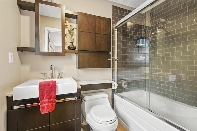 full bath featuring toilet, a sink, and shower / bath combination with glass door