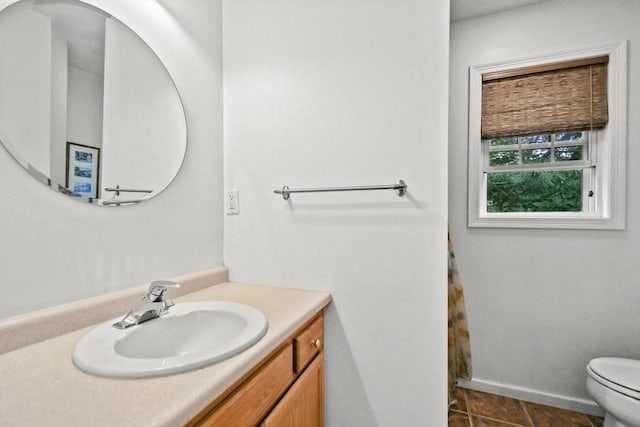 bathroom with toilet, vanity, and baseboards