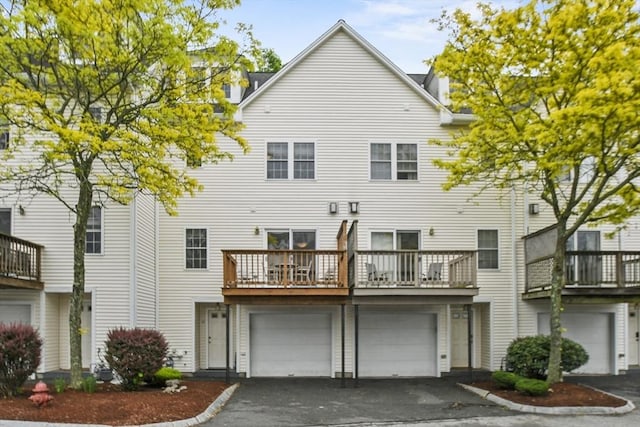rear view of house featuring asphalt driveway, an attached garage, and a balcony