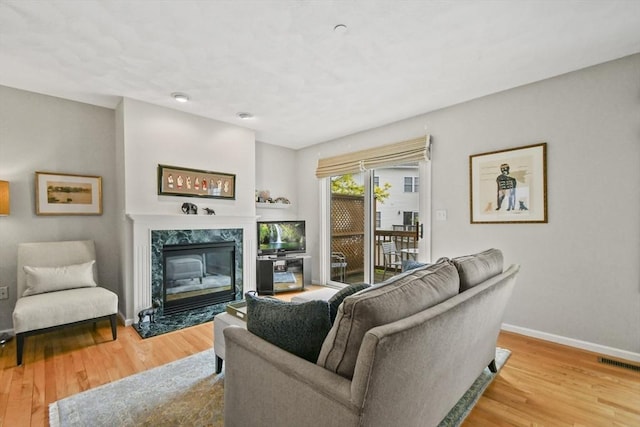 living area with a high end fireplace, wood finished floors, and baseboards