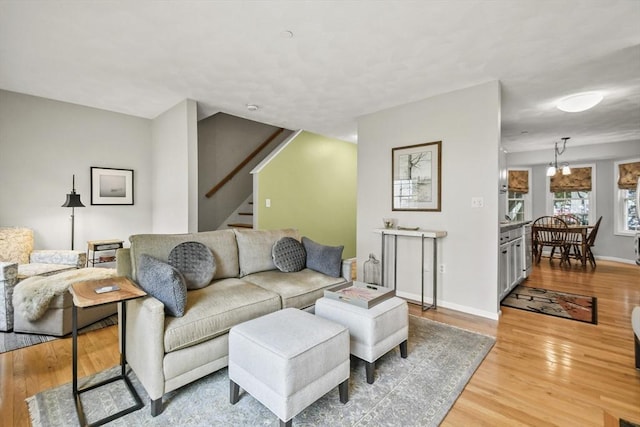 living room with light wood-type flooring, stairway, and baseboards