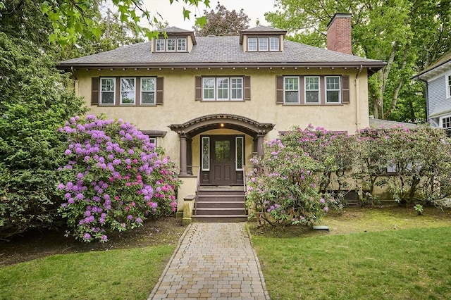 92 Dean Rd, Brookline, MA 02445 - view of front of house with stucco siding, a chimney, and a front lawn