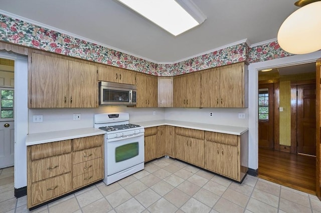92 Dean Rd, Brookline, MA 02445 - kitchen with white gas range oven, stainless steel microwave, light countertops, light tile patterned flooring, and crown molding