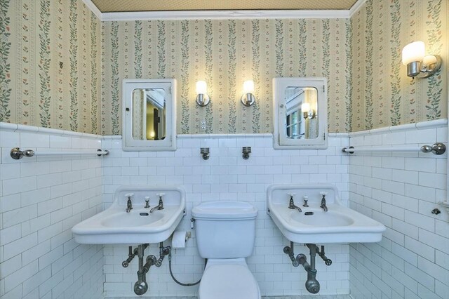 92 Dean Rd, Brookline, MA 02445 - half bathroom with wallpapered walls, wainscoting, toilet, a sink, and tile walls