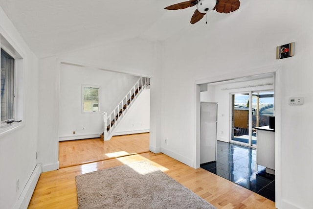 interior space with a baseboard radiator, vaulted ceiling, ceiling fan, and hardwood / wood-style flooring