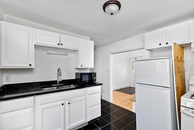 kitchen with white appliances, white cabinetry, dark tile patterned floors, and sink