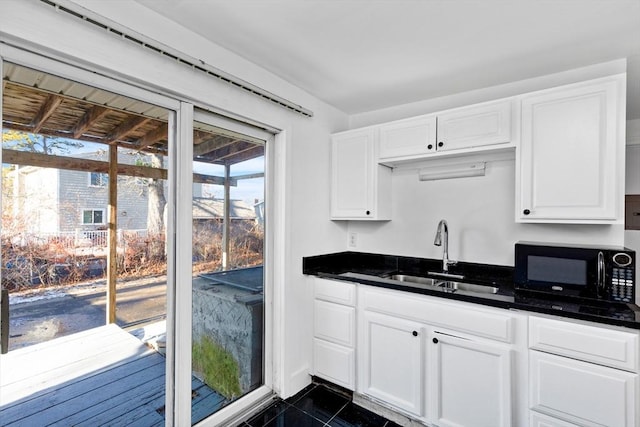 kitchen with white cabinetry, dark tile patterned floors, and sink