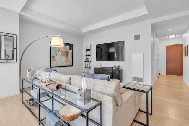 living room featuring light hardwood / wood-style flooring and a raised ceiling