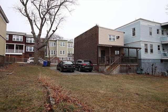 rear view of property featuring a yard and covered porch