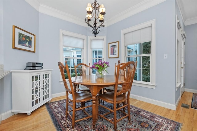 dining area featuring visible vents, light wood-style flooring, an inviting chandelier, crown molding, and baseboards