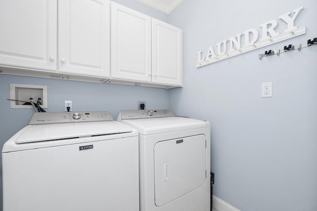 clothes washing area featuring washing machine and dryer, cabinet space, and baseboards