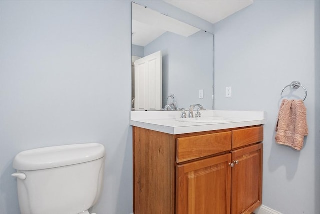 bathroom with baseboards, toilet, and vanity