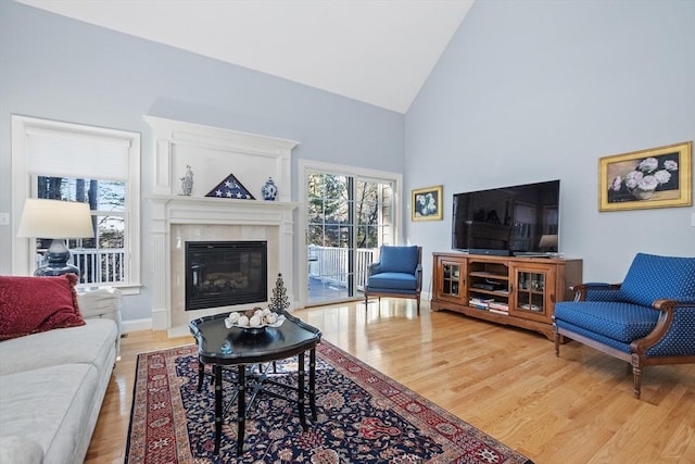 living room with high vaulted ceiling, baseboards, light wood-style floors, and a fireplace