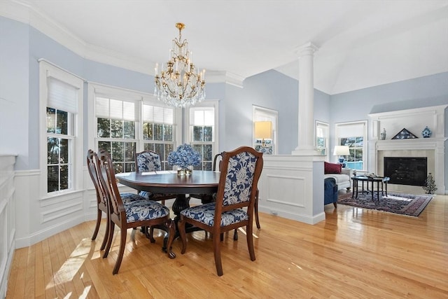 dining space featuring decorative columns, a healthy amount of sunlight, and a fireplace