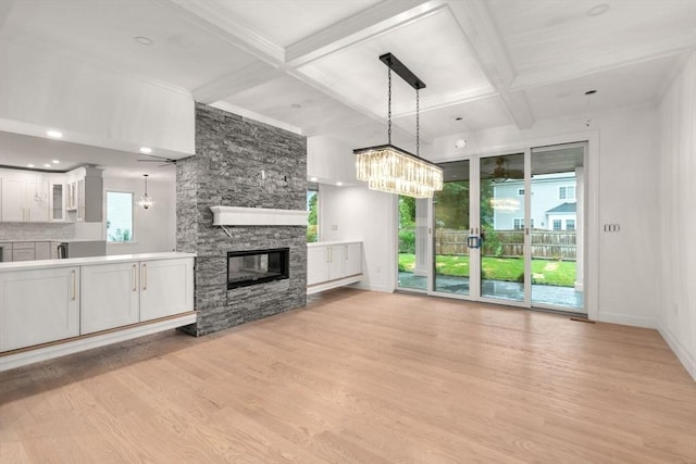 57 Mayflower Rd, Needham, MA 02492 - unfurnished living room with beamed ceiling, a stone fireplace, light wood-style flooring, coffered ceiling, and baseboards