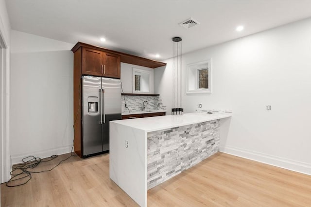 57 Mayflower Rd, Needham, MA 02492 - kitchen featuring stainless steel fridge with ice dispenser, a peninsula, light wood-type flooring, backsplash, and light countertops