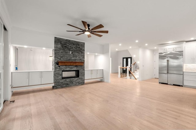 57 Mayflower Rd, Needham, MA 02492 - unfurnished living room featuring a ceiling fan, a stone fireplace, light wood-style flooring, recessed lighting, and stairs