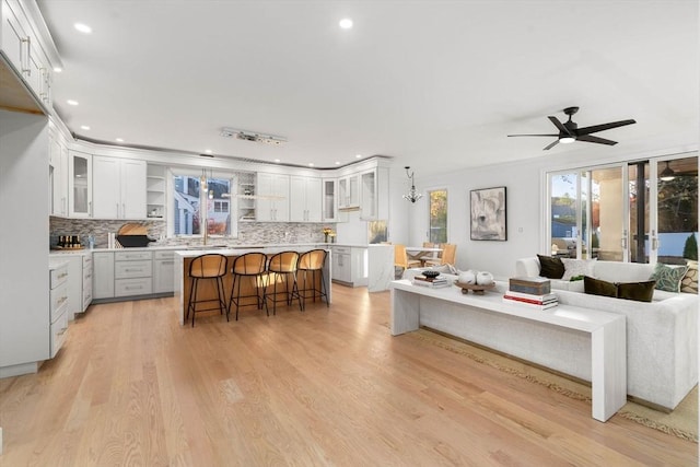 57 Mayflower Rd, Needham, MA 02492 - kitchen featuring open floor plan, a breakfast bar area, tasteful backsplash, white cabinets, and recessed lighting
