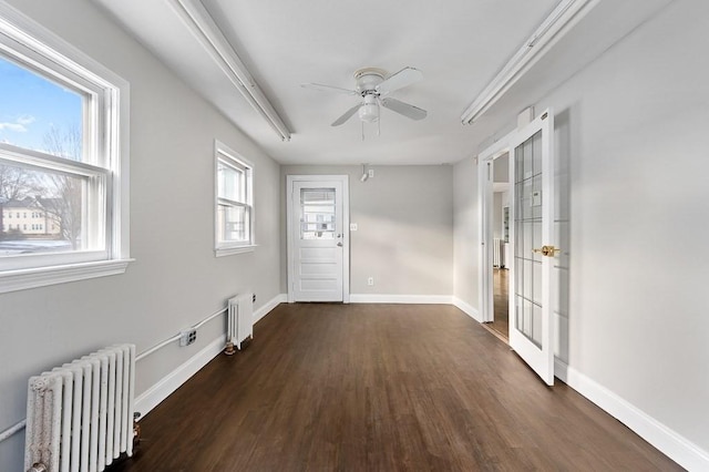 empty room featuring radiator heating unit, dark wood-type flooring, and a wealth of natural light