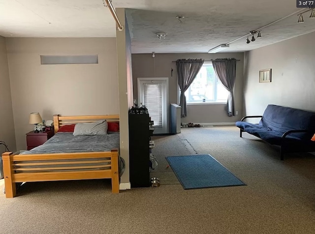 carpeted bedroom featuring track lighting