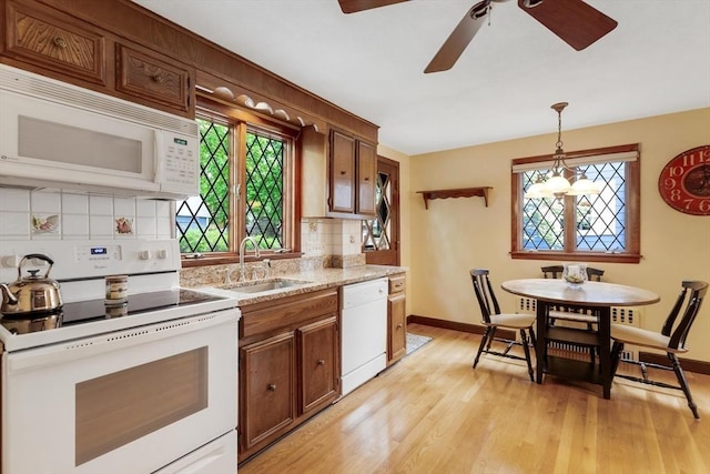 kitchen featuring white appliances, a ceiling fan, a sink, light wood-style flooring, and tasteful backsplash
