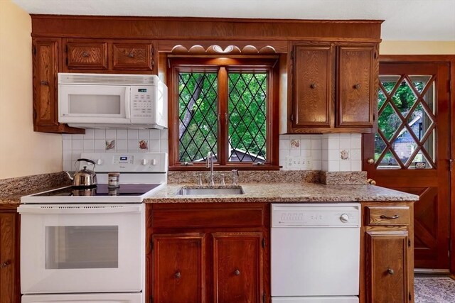 kitchen featuring white appliances, a sink, decorative backsplash, and brown cabinetry