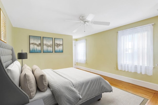 bedroom featuring baseboards, wood finished floors, and a ceiling fan