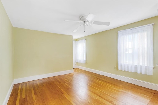 empty room featuring healthy amount of natural light, baseboards, and light wood-type flooring