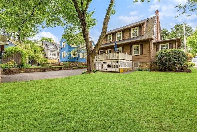 back of house with a chimney and a lawn