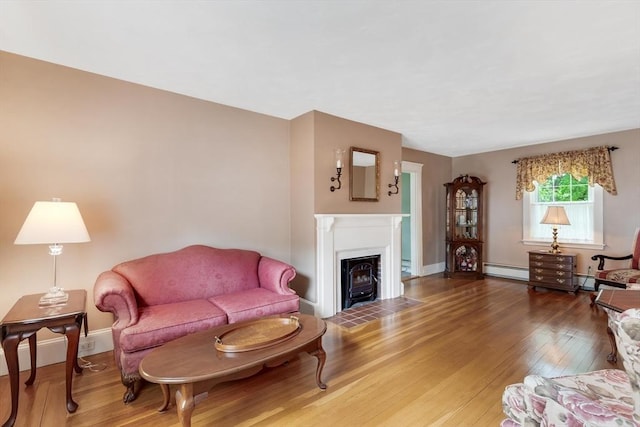 living room featuring hardwood / wood-style floors, a fireplace with flush hearth, baseboard heating, and baseboards