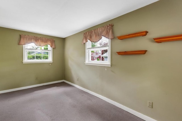 carpeted spare room featuring healthy amount of natural light and baseboards