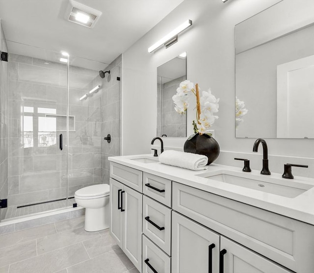 bathroom with toilet, tile patterned flooring, a shower with door, and vanity