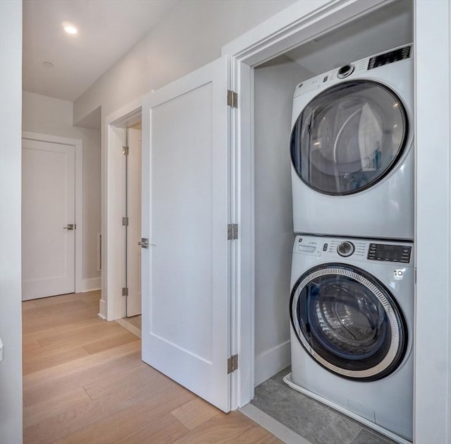 laundry area featuring stacked washer and clothes dryer and light hardwood / wood-style floors