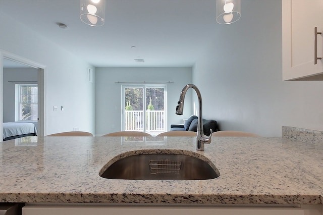 kitchen featuring sink, light stone counters, and pendant lighting