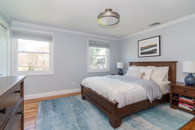 bedroom featuring baseboards, visible vents, ornamental molding, and light wood-type flooring