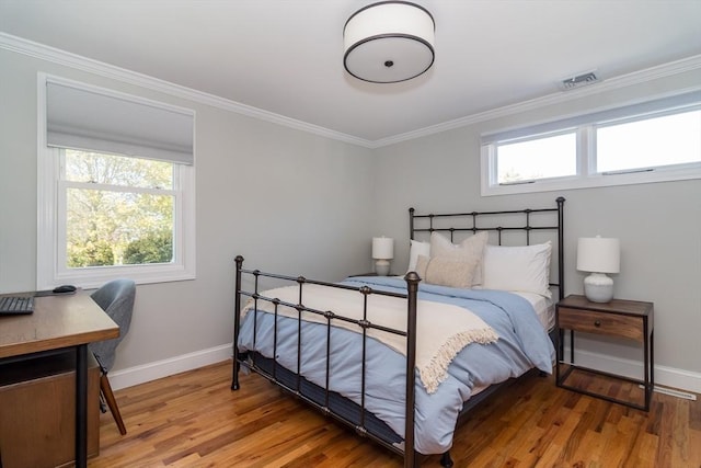 bedroom with visible vents, baseboards, crown molding, and wood finished floors